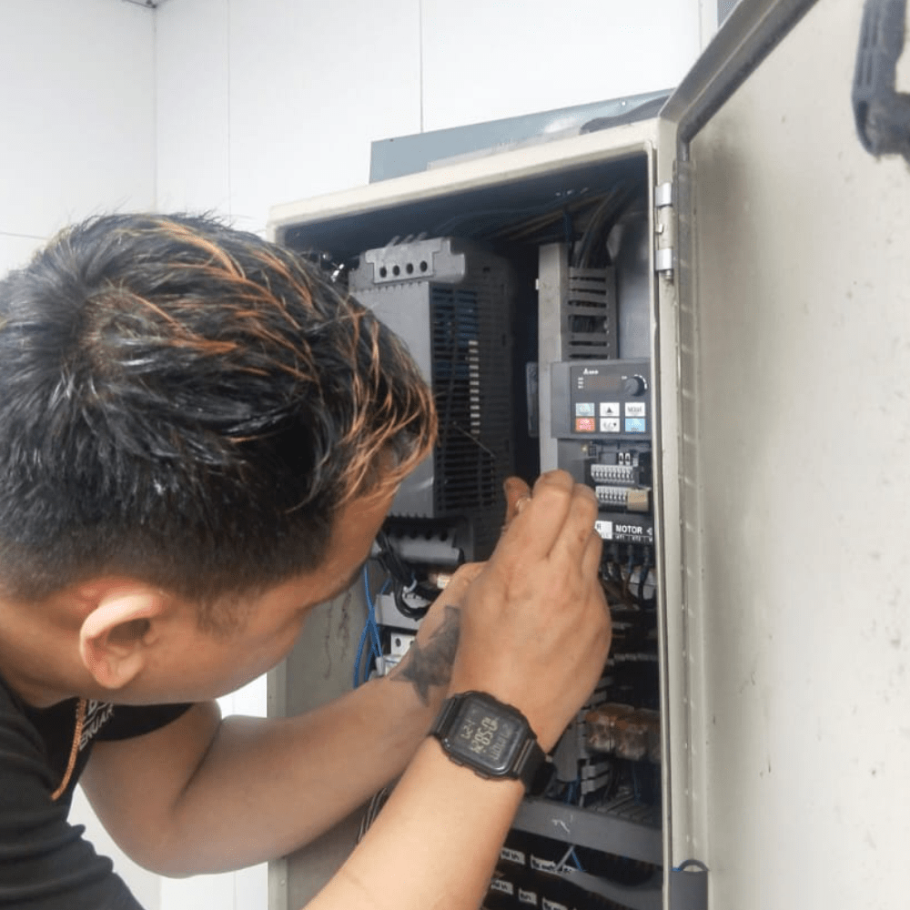Technician inspecting an electrical control panel for commercial kitchen ventilation and M&E maintenance in Singapore